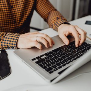 A man typing on a laptop in a modern office setting, showcasing technology and work life.