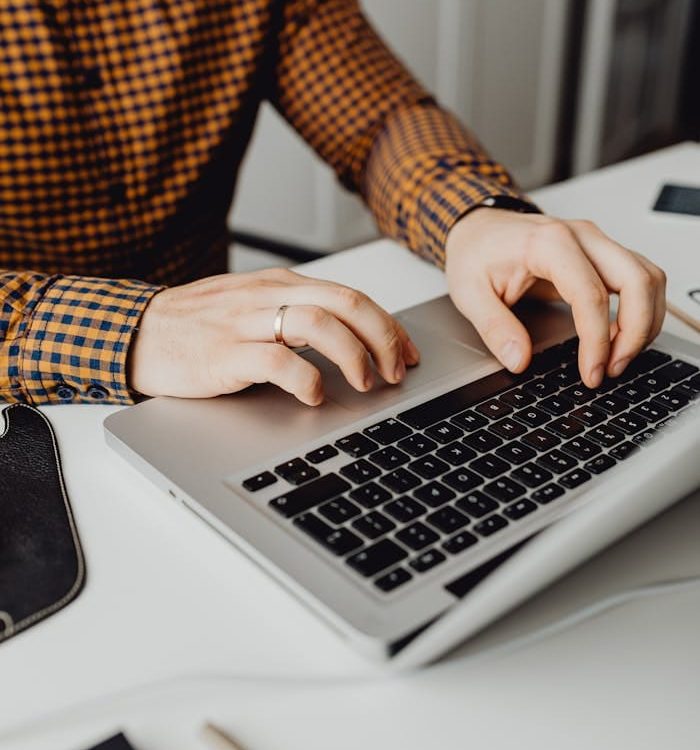 A man typing on a laptop in a modern office setting, showcasing technology and work life.