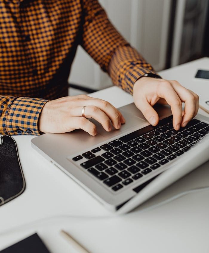 A man typing on a laptop in a modern office setting, showcasing technology and work life.